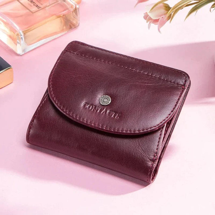 Vue de dessus d'un portefeuille compact en cuir pour femme, coloris bordeaux, montrant texture et surpiqûres fines.