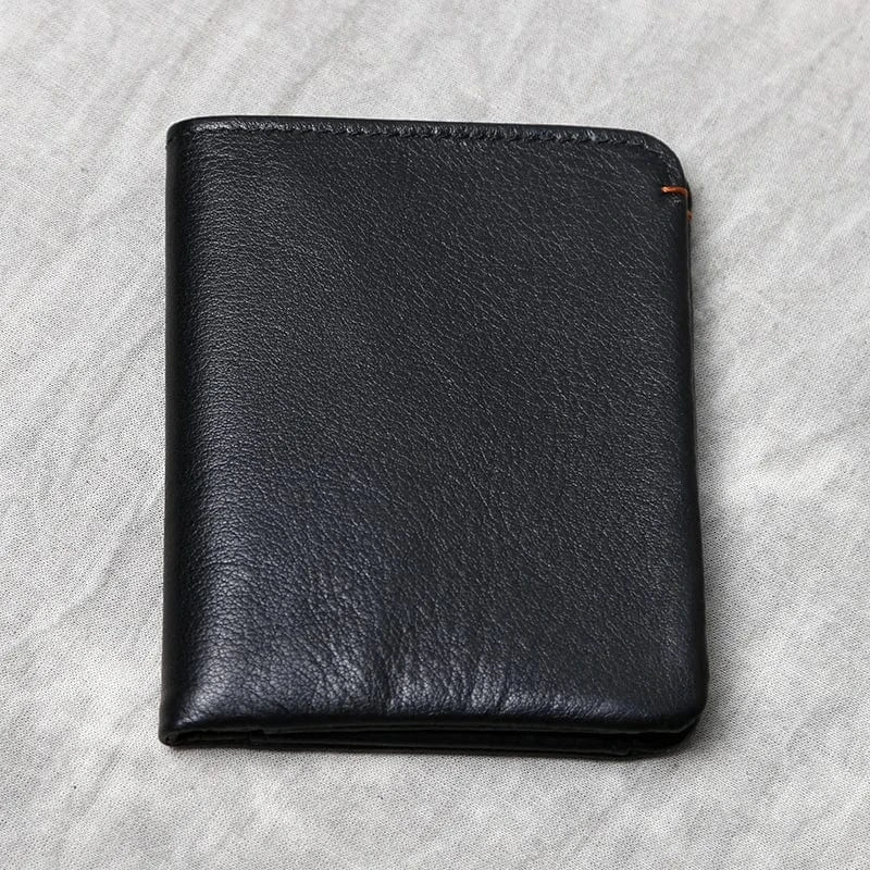 Portefeuille fin en cuir artisanal pour hommes, noir, ouvert révélant compartiments cartes et billets.