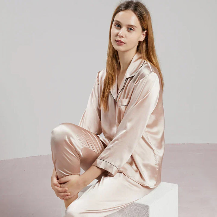 Femme se relaxant dans un pyjama satiné à manches longues, symbolisant le confort et la détente des vêtements de nuit.