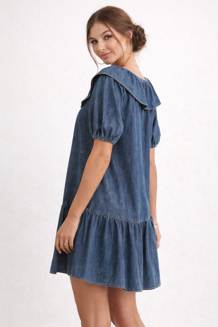 Femme portant une robe en jean courte et élégante avec manches bouffantes, look décontracté chic.
