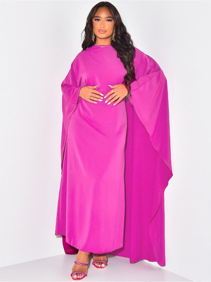 Femme portant une robe de soirée chic avec des manches chauve-souris, idéale pour toute occasion spéciale. Très élégante.