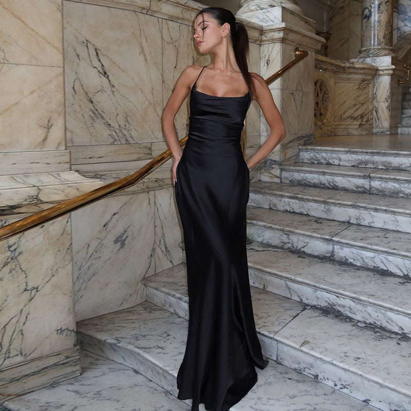 Robe longue satinée noire dos nu élégante, coupe fluide, satin luxueux, lacets croisés, style soirée sophistiqué.