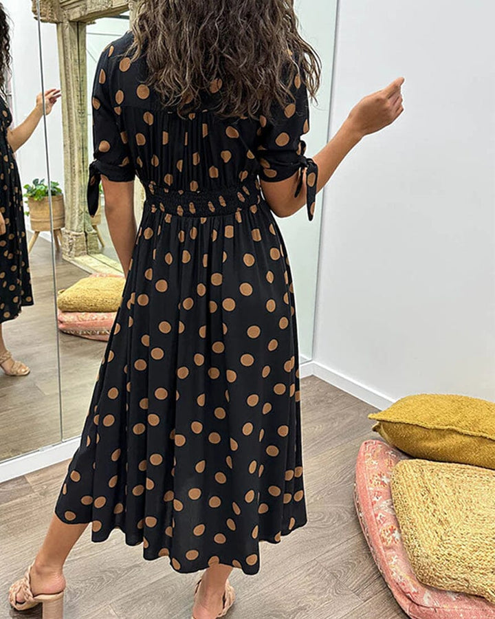 "Robe mi-longue à pois, manches nouées, coupe cintrée, imprimé rétro, parfaite pour occasions élégantes."