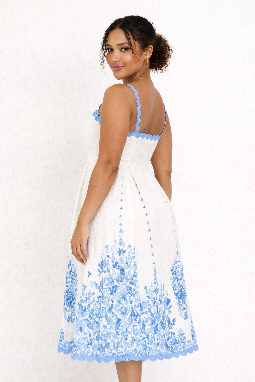 Femme portant une robe midi imprimée fluide à bretelles, coupe décontractée chic, idéale pour tenue estivale.