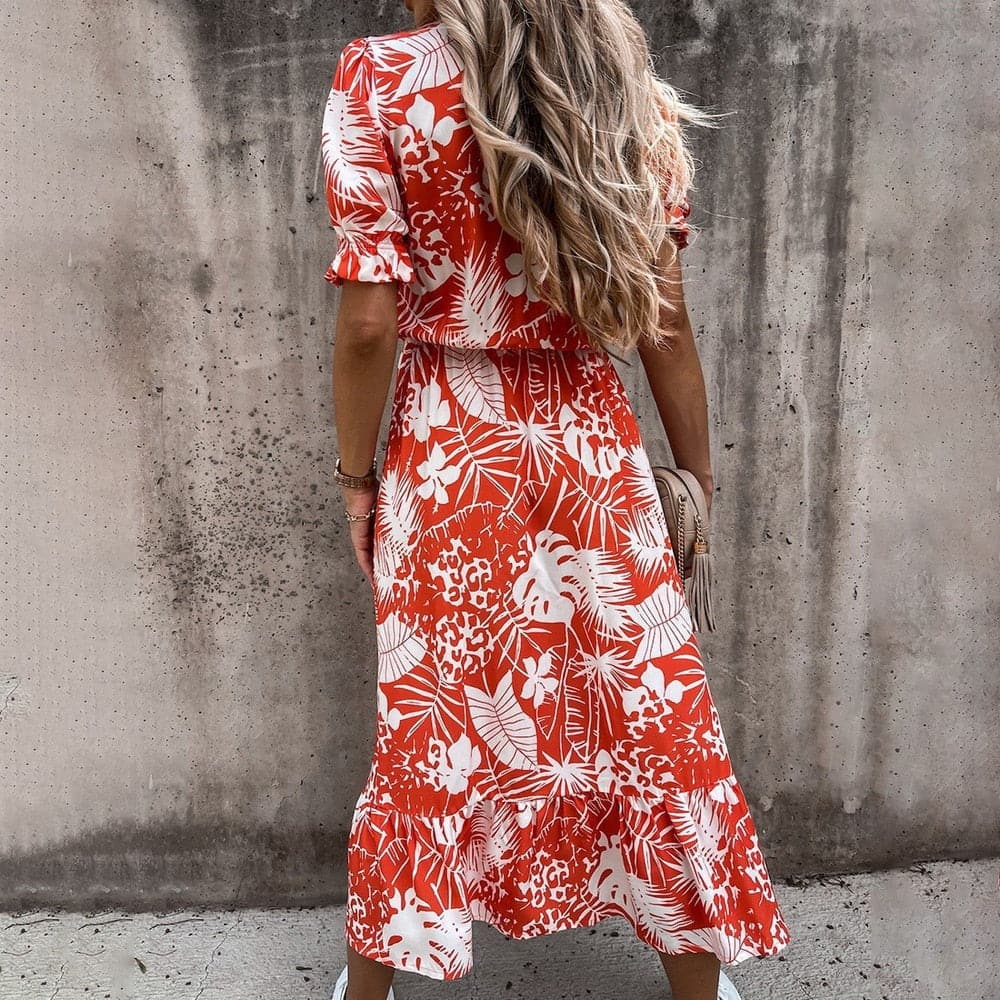 "Robe midi portefeuille rouge en coton avec motif tropical blanc, décolleté en V, manches courtes, silhouette enveloppante."
