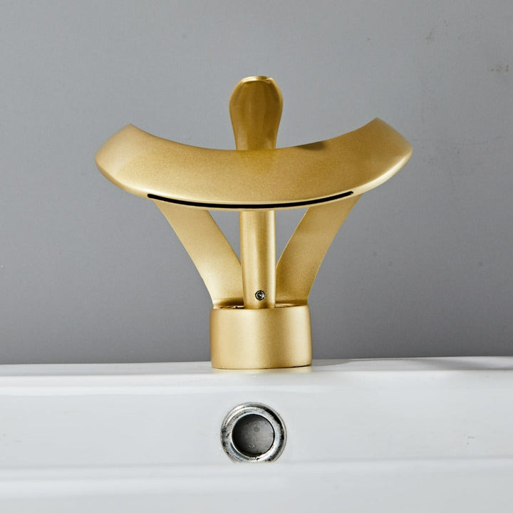 Robinet cascade doré brossé pour salle de bain. Design moderne et luxueux.