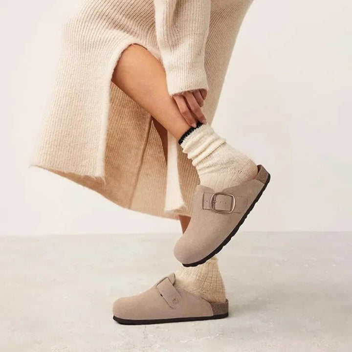Sabots confortables pour femme, en cuir suédé doux, avec détail de boucle dorée.