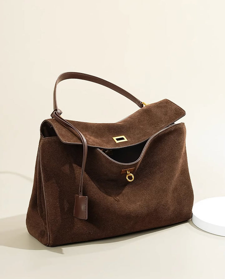 "Sac à main AMÉLIE en daim véritable, automne-hiver, élégant avec fermeture dorée et bandoulière réglable."