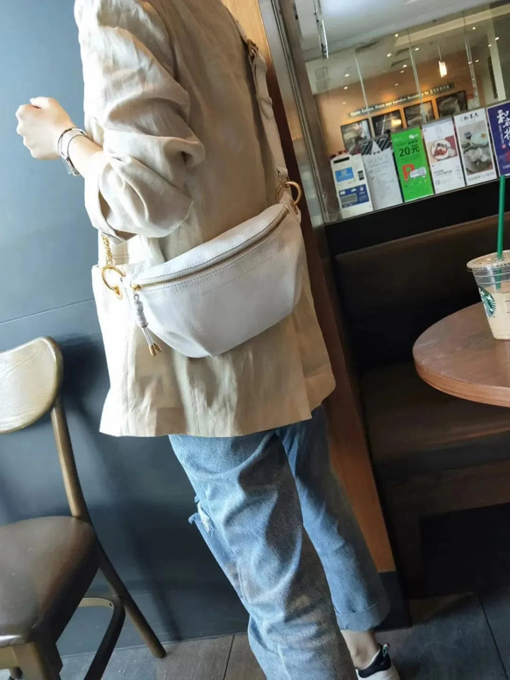 Sac banane Cleopatra en cuir véritable beige posé à plat, montrant son design élégant et compact.