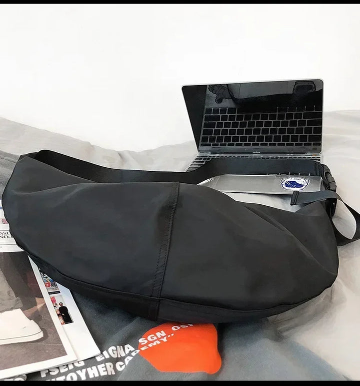 Sac banane de voyage XXL noir en nylon, léger et pratique pour femme, porté en bandoulière.