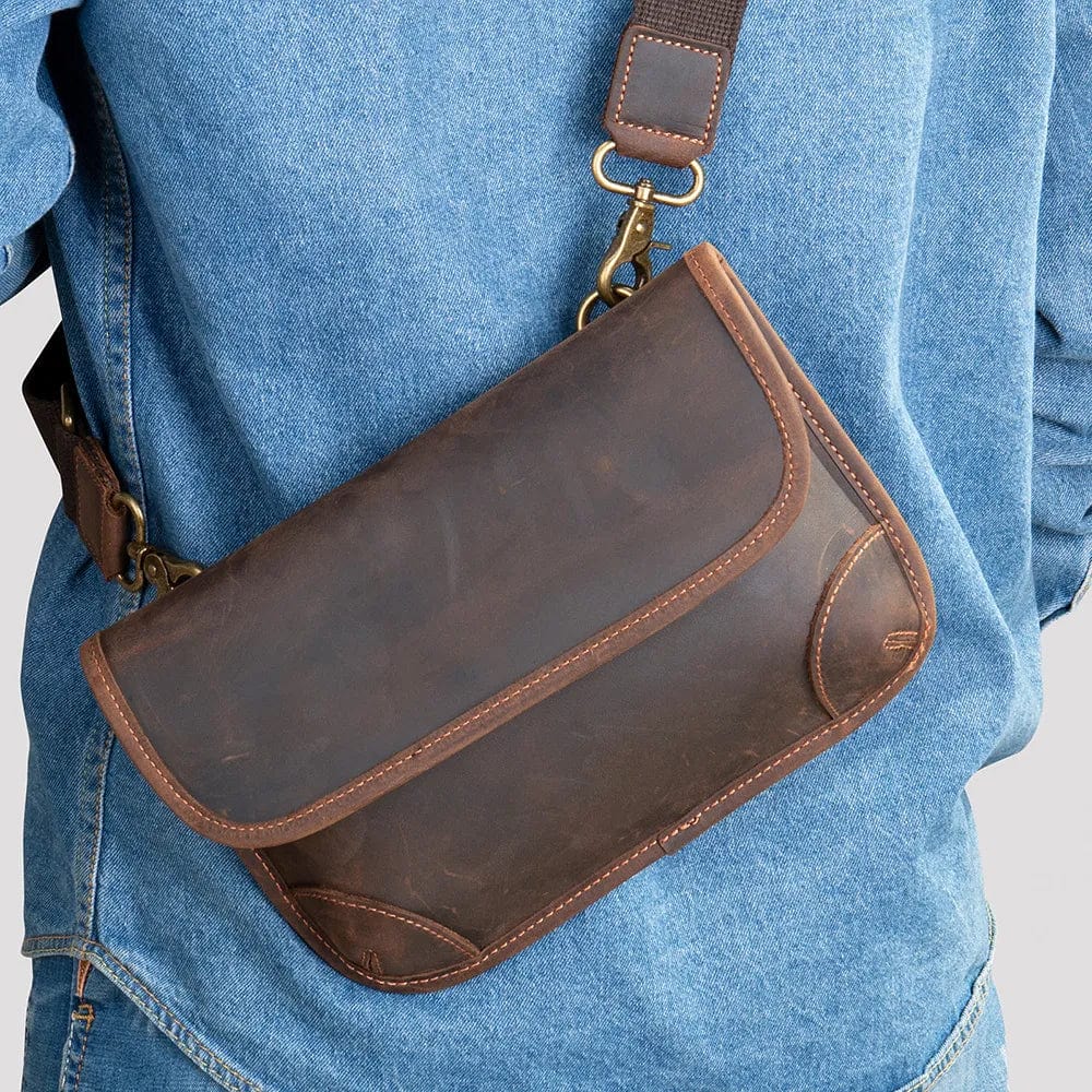Sac banane homme en cuir véritable marron café, élégance moderne, porté bandoulière sur fond urbain.