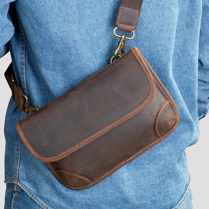 Sac banane homme en cuir véritable marron café, élégance moderne, porté bandoulière sur fond urbain.