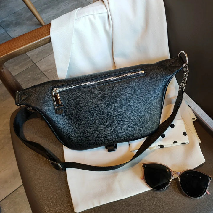 Sac banane en cuir noir pour femme, porté à la taille, accessoire polyvalent pour un look tendance.