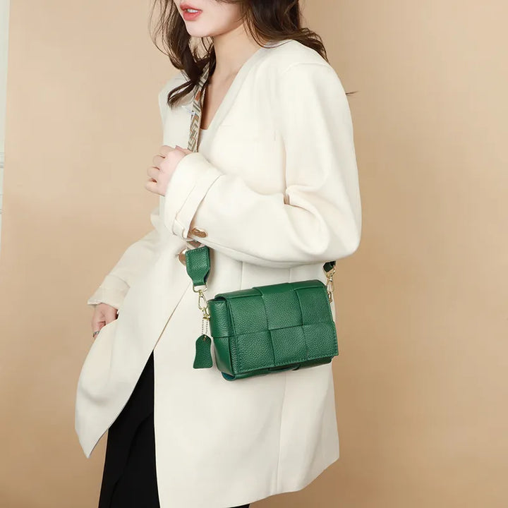 Gros plan sur un sac bandoulière en cuir vert émeraude, présentant sa texture et sa finition élégante.