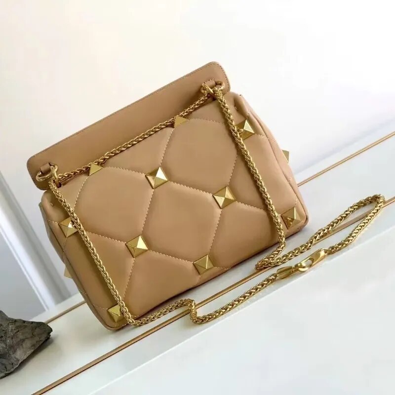 Détail du sac bandoulière en cuir noir, fermeture éclair, clous décoratifs et chaîne