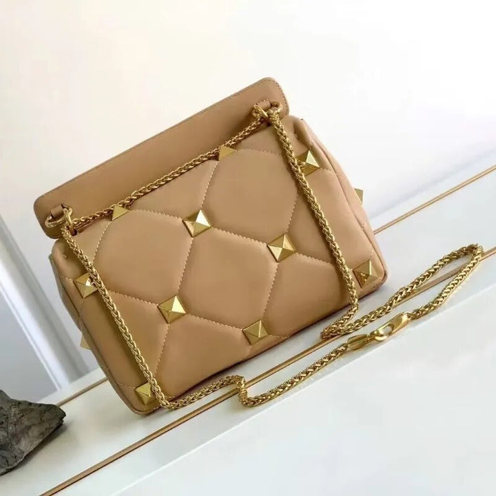 Détail du sac bandoulière en cuir noir, fermeture éclair, clous décoratifs et chaîne
