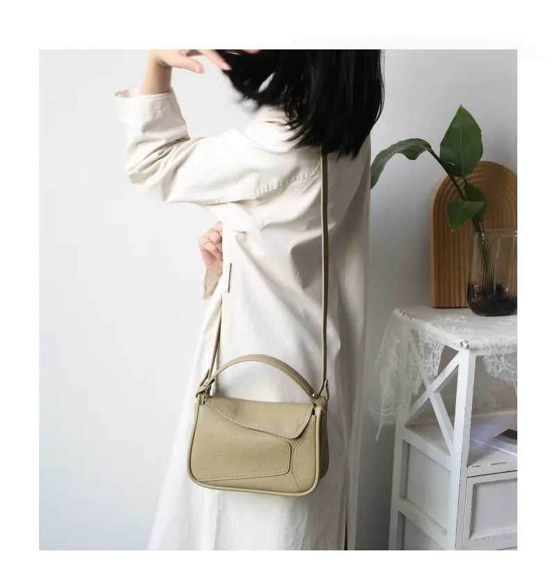 Sac bandoulière femme en cuir véritable, porté sur l'épaule, montrant son style élégant.