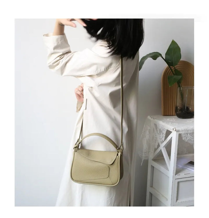 Sac bandoulière femme en cuir véritable, porté sur l'épaule, montrant son style élégant.