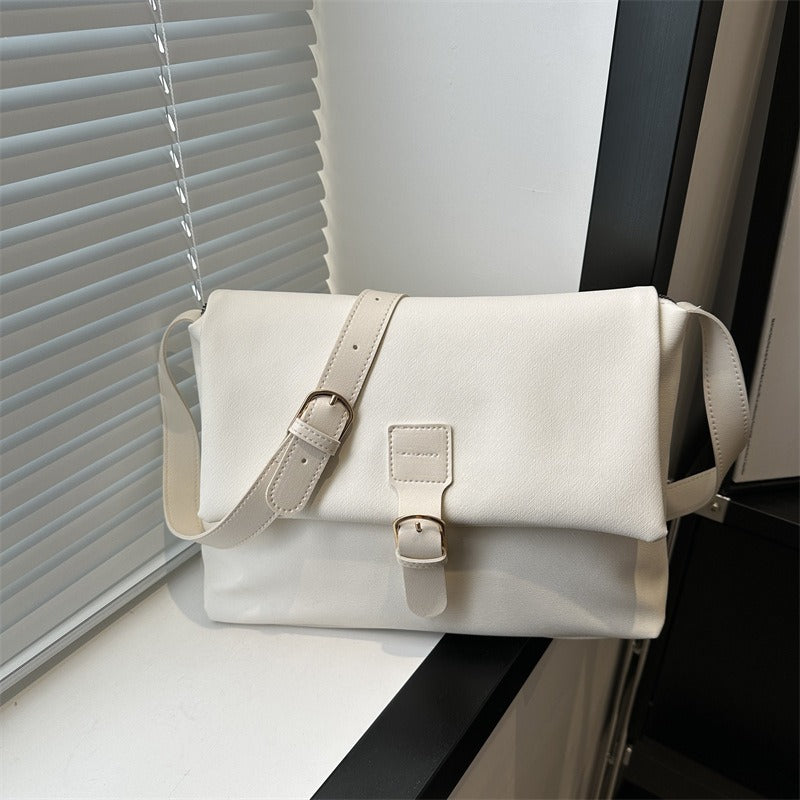 Sac à bandoulière femme élégant posé sur table. Cuir synthétique minimaliste, accessoire de mode polyvalent et chic.