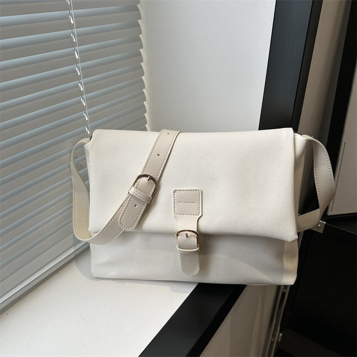 Sac à bandoulière femme élégant posé sur table. Cuir synthétique minimaliste, accessoire de mode polyvalent et chic.