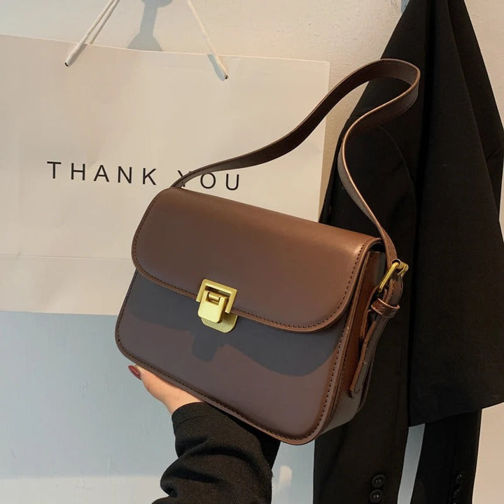 Vue de côté du sac à bandoulière femme noir. Forme structurée, design épuré, chic et contemporain.