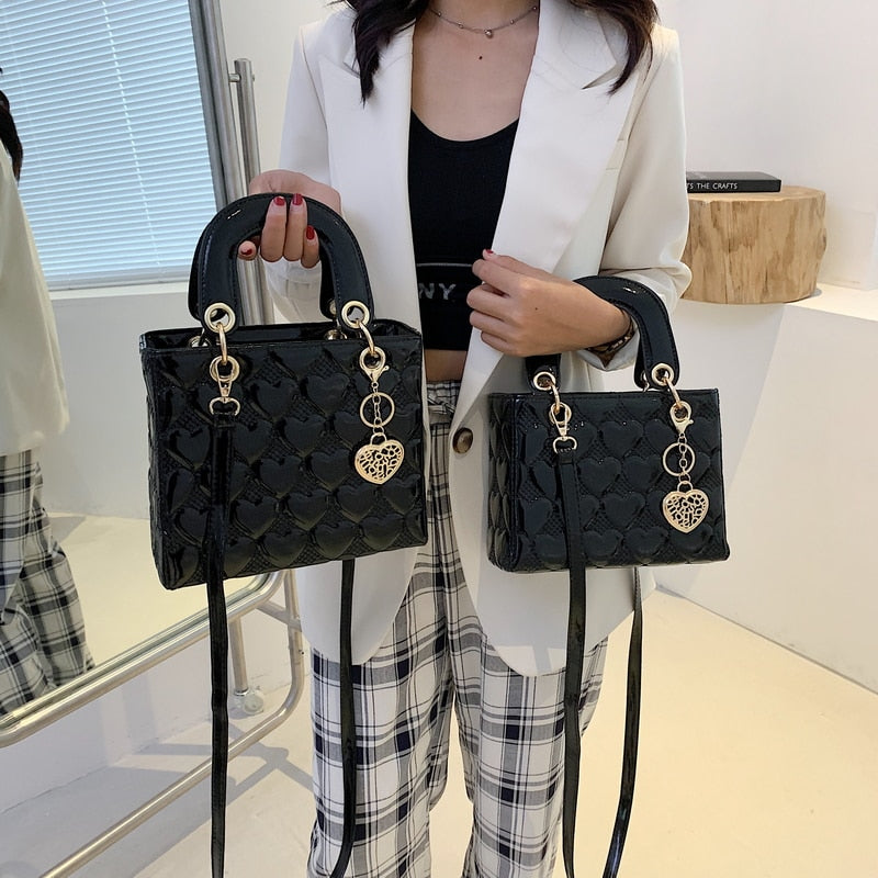 Sac à main femme noir brillant, bandoulière discrète, parfait accessoire mode élégant pour femme.