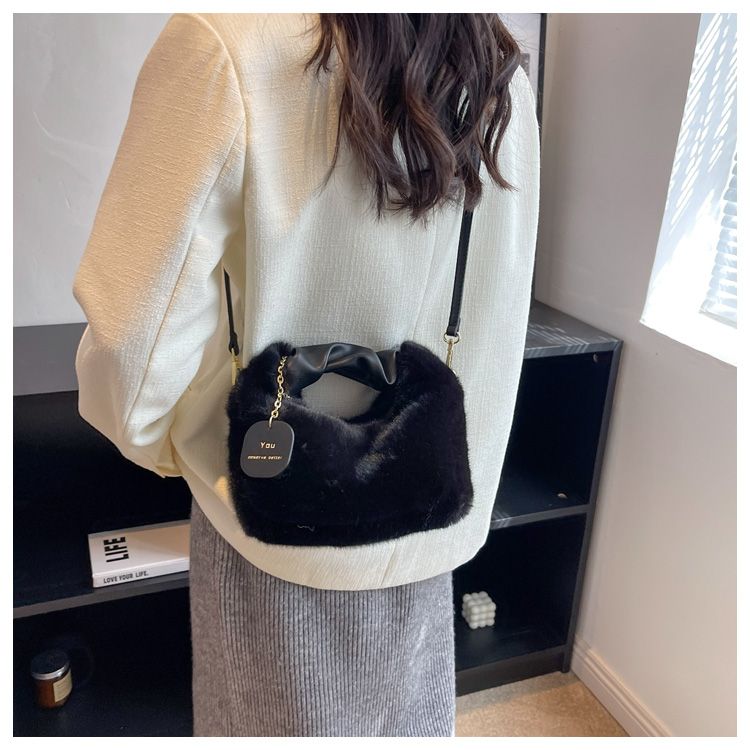 Sac à main pochette en fausse fourrure noire pour femme, idéal pour compléter une tenue hivernale chic.