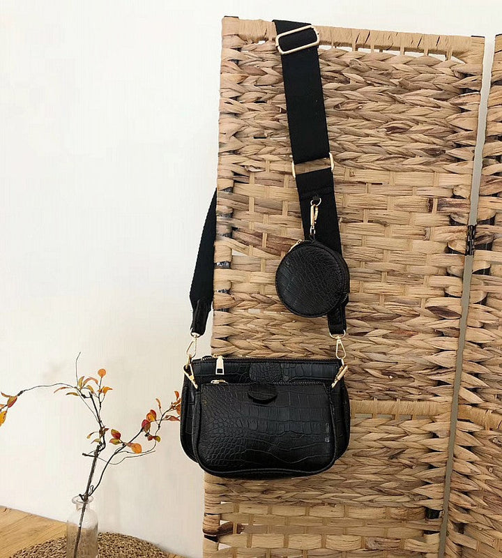 Détail gros plan sac bandoulière femme noir, motif croco brillant, fermoir discret, élégant