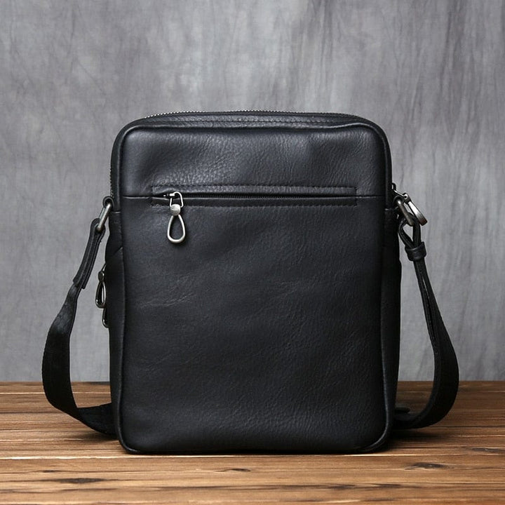Vue latérale du sac bandoulière Aaron en cuir pour homme, noir, mettant en valeur sa finesse et son design épuré.