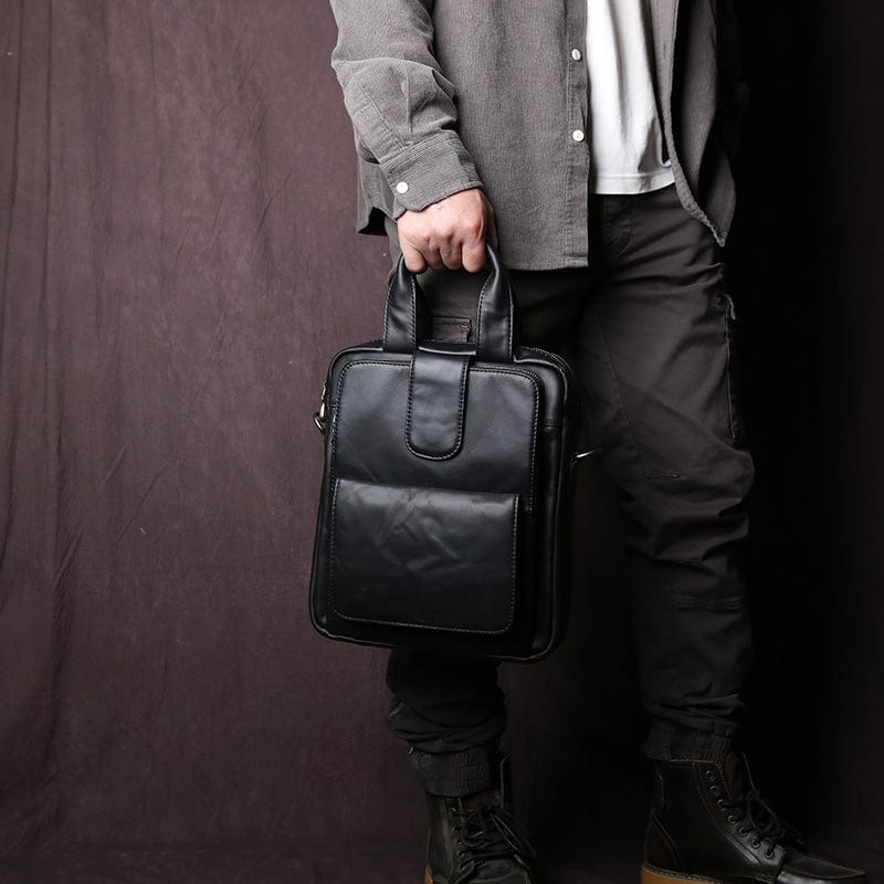 Gros plan sur la finition du cuir d'un sac bandoulière homme, couleur noir profond et toucher doux.