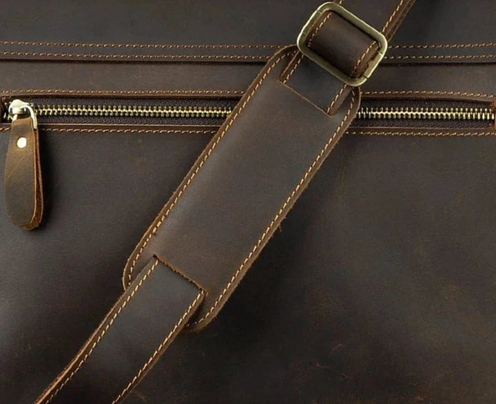 Gros plan sur la texture du cuir véritable lisse du sac bandoulière homme, couleur café riche.