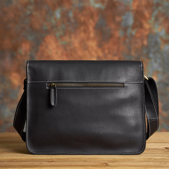 Sac messager en cuir noir, adapté pour homme, avec une poche avant facile d'accès.