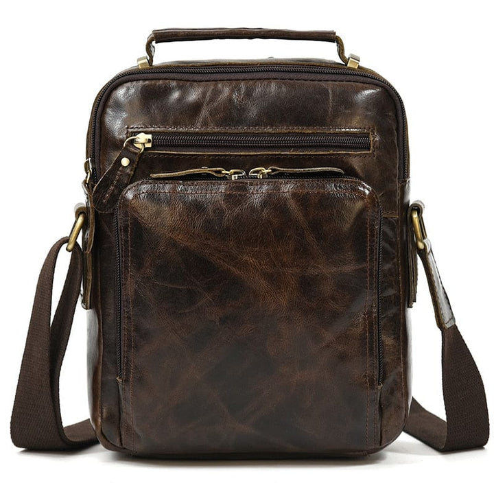 Maroquinerie homme: sac bandoulière en cuir noir avec boucles métalliques décoratives.