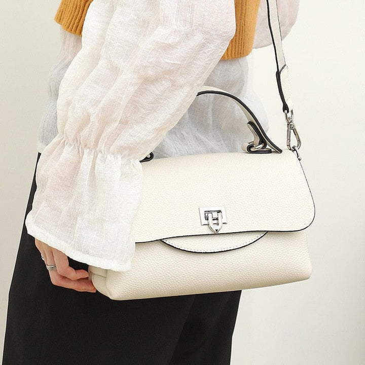 Sac femme en cuir grainé bleu marine, doté d'une longue bandoulière et d'une fermeture sécurisée.