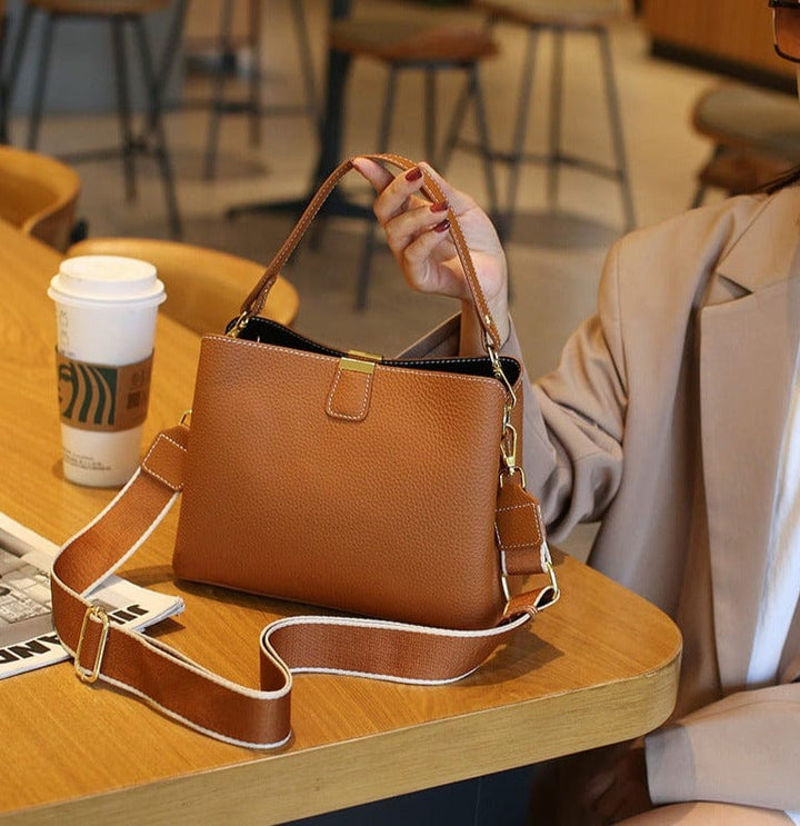 Sac à main en cuir véritable pour femme, de couleur bordeaux, porté par une femme en robe. Touche de couleur sophistiquée.