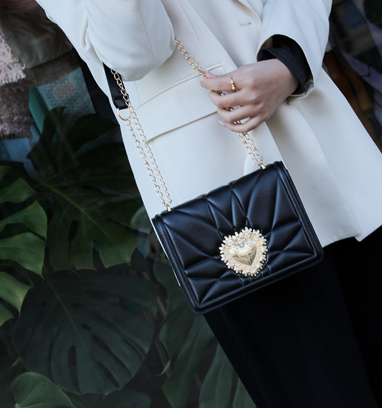 Accessoire tendance : sac à main noir en bandoulière pour femme, avec détails dorés, pour un look élégant et chic.