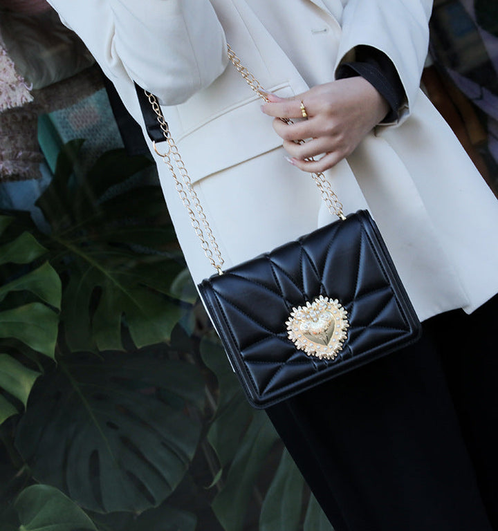 Accessoire tendance : sac à main noir en bandoulière pour femme, avec détails dorés, pour un look élégant et chic.