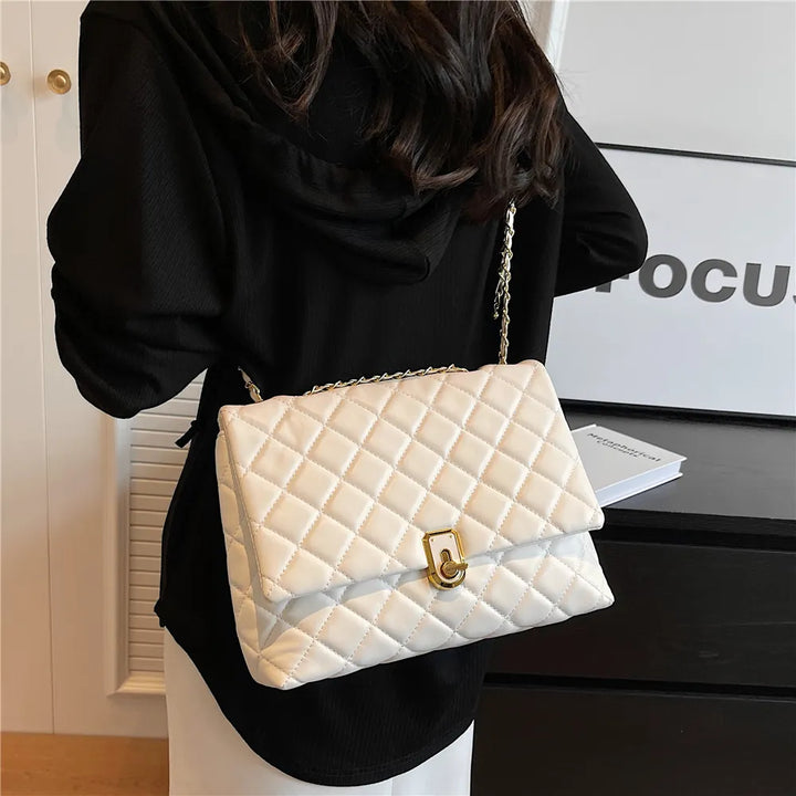 Sac bandoulière matelassé femme avec chaîne dorée, porté à l'épaule, accessoire de mode pratique.