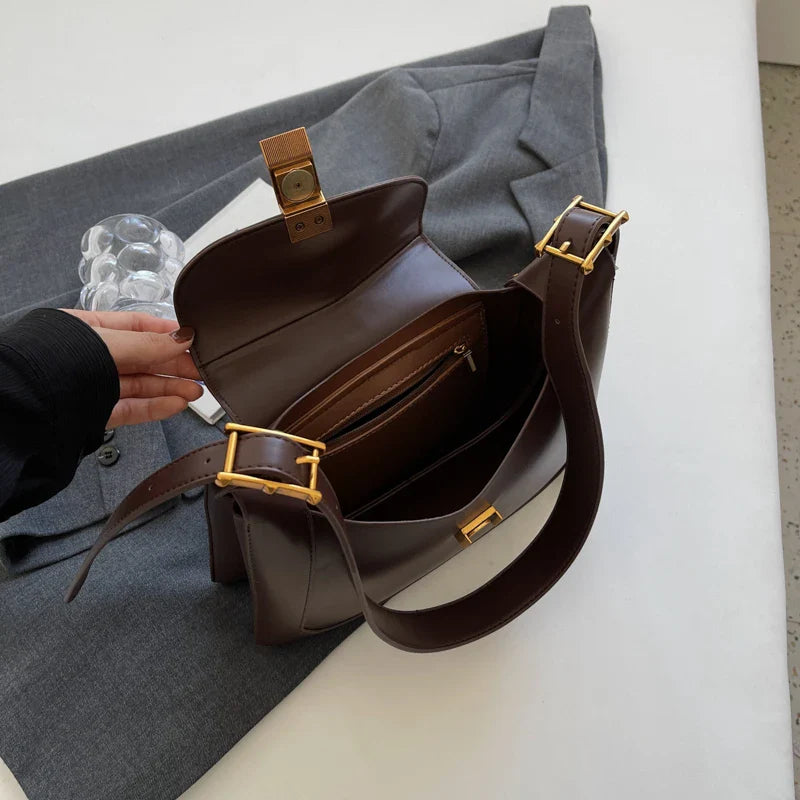 Sac à bandoulière noir pour femme, porté à l'épaule, accentuant son design chic et pratique.