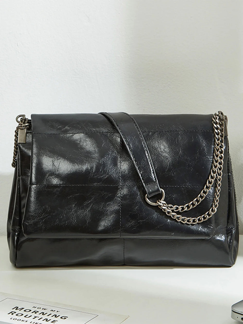 Sac à épaule femme chic noir en similicuir, bandoulière réglable, accessoire de mode urbain.