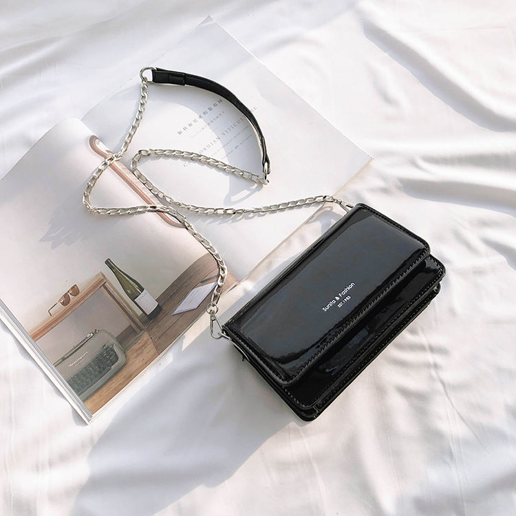 Sac bandoulière noir vernis élégant pour femme, chic et compact, idéal accessoire quotidien.