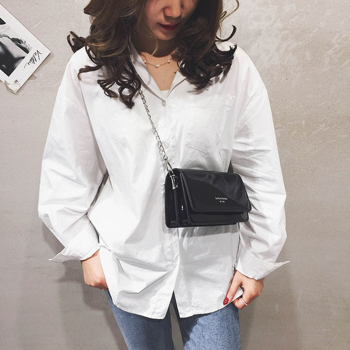 Sac bandoulière femme noir vernis, compact et élégant, un accessoire chic pour le quotidien.