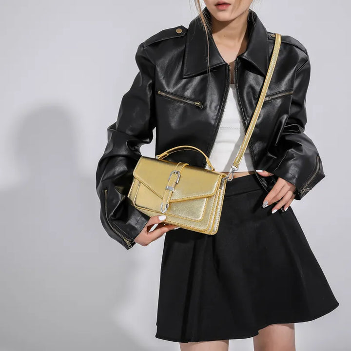 Gros plan sur le sac bandoulière Petra doré, fermeture éclair, texture cuir synthétique, accessoire mode.