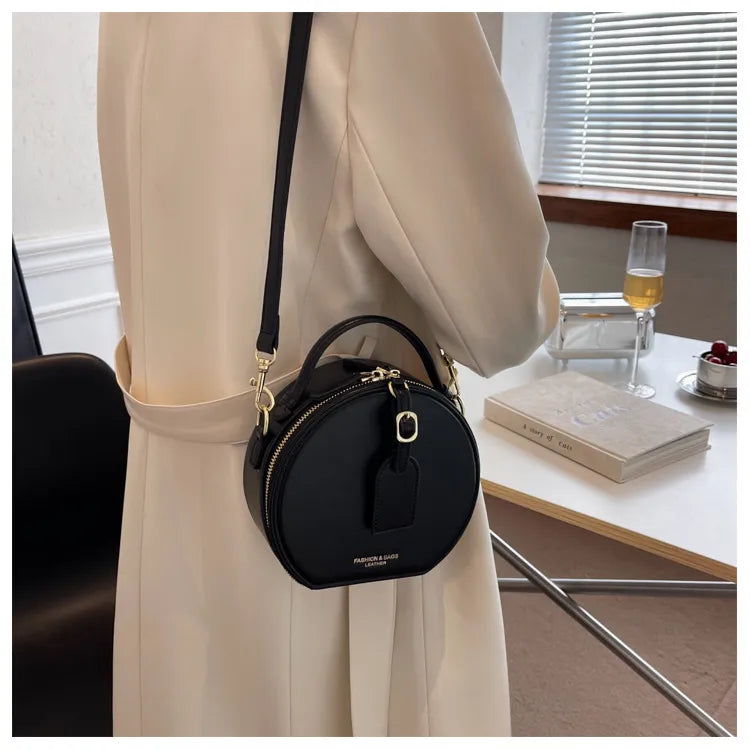 Sac rond en similicuir noir pour femme, bandoulière ajustable, look mode.