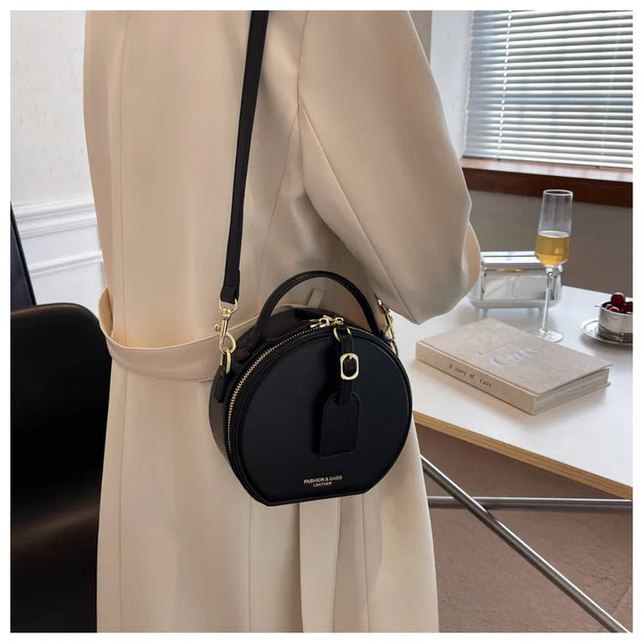 Sac rond en similicuir noir pour femme, bandoulière ajustable, look mode.