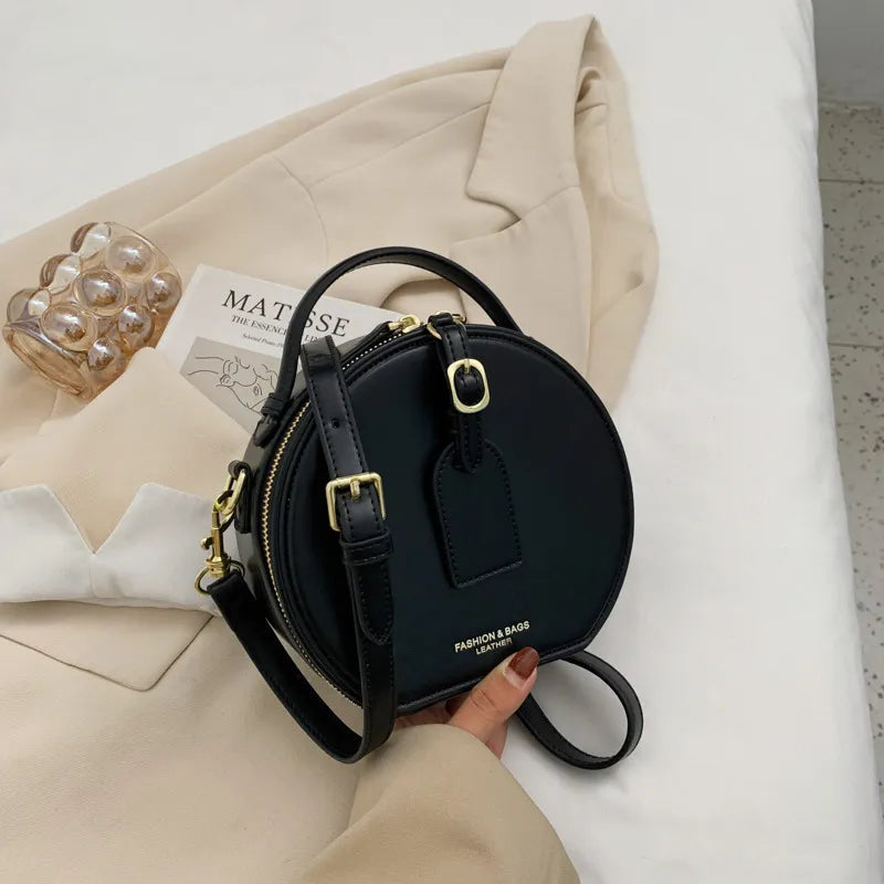 Sac à main rond en cuir bordeaux, bandoulière fine, idéal pour un look élégant.