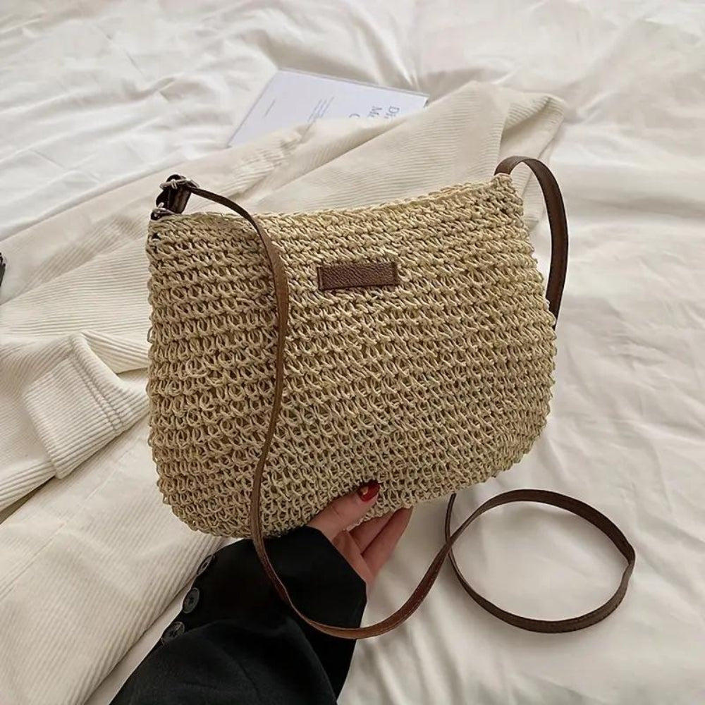 "Sac bandoulière Léandre en paille premium avec finitions cuir végan, bandoulière ajustable et fermeture éclair sécurisée."