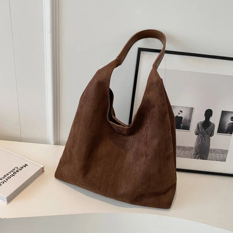 Sac besace femme en daim, porté épaule ou bandoulière. Élégant et pratique pour le quotidien ou soirées.