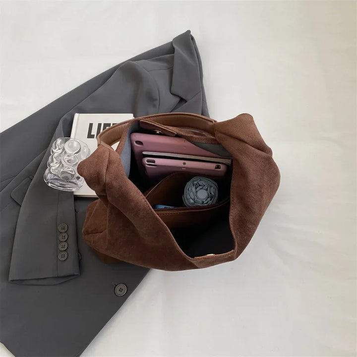 Sac besace en daim marron, vue arrière. Poche zippée, design élégant et pratique pour ce sac épaule femme.