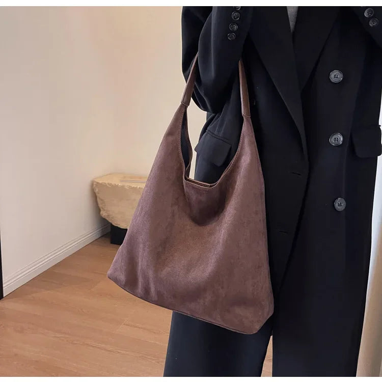 Détail fermeture dorée sac besace daim. Maroquinerie élégante, accessoire mode chic et raffiné pour femme.